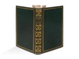 un vieux livre à la couverture verte posé sur une surface blanche