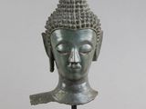 tête en bronze d'une statue de Bouddha posée sur un socle en bois