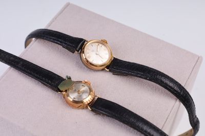 une paire de montres à bracelet en cuir noir et boîtier doré sur fond blanc