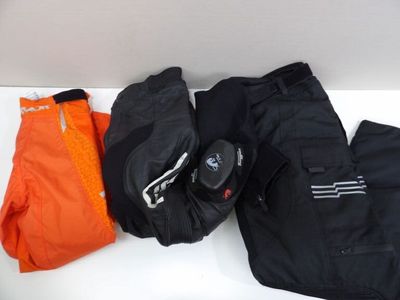 three pairs of pants and a pair of gloves on a white table