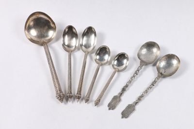 six cuillères en argent et des cuillères à soupe sont alignées sur une surface blanche