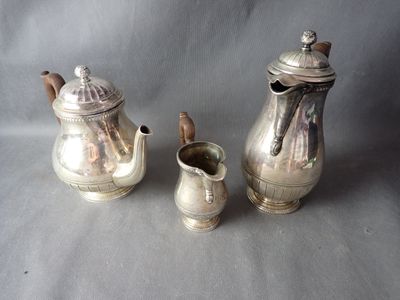 two silver teapots and a sugar shaker on a table