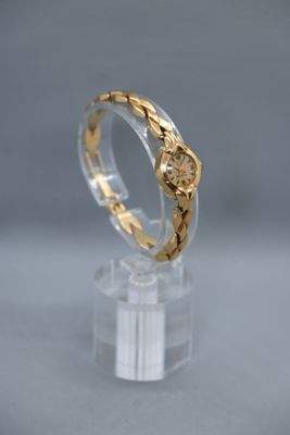 un gros plan d'une bague en or posée sur une surface transparente