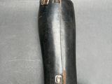 someone is holding a pair of black leather boots on a gray surface