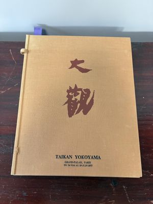 a brown book sitting on top of a wooden table next to a white wall