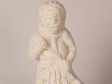 statue of a woman sitting on a rock with her hands crossed