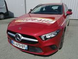 La Mercedes CLA est garée devant un immeuble sur lequel est accrochée une pancarte « À vendre ».