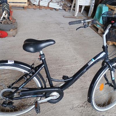 un vélo noir garé dans un garage, avec un panier à l'arrière