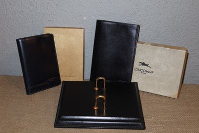 trois portefeuilles en cuir noir posés sur une table à côté d'une boîte