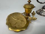 une assiette en or et une coupe en argent posées sur une table blanche