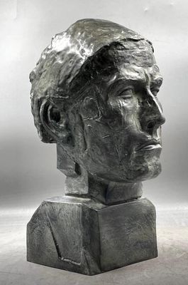 sculpture représentant une tête d'homme sur un socle, avec un fond gris