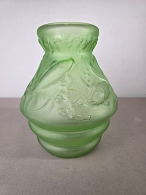 un vase vert posé sur une table avec un mur blanc en arrière-plan
