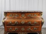 une commode ancienne avec un plateau en marbre, posée sur un parquet