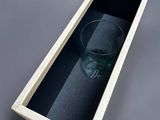 a glass in a wooden box on a gray surface