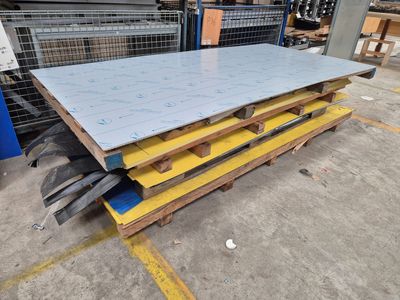 une pile de tôles d'acier dans un entrepôt, posées sur des palettes