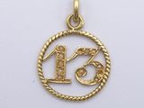 a close up of a gold pendant with the number thirteen on it