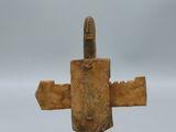 une vieille sculpture en bois représentant un homme tenant un couteau, posée sur un socle