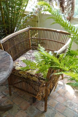 une chaise en osier et une table sur une terrasse en briques