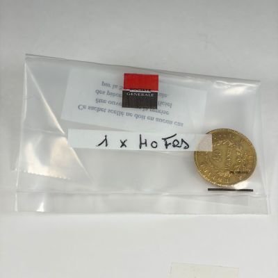 une pièce d'or dans un sachet en plastique transparent sur lequel est collé un autocollant
