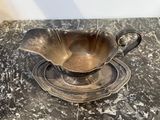 a silver bowl and saucer sitting on a marble table