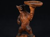 une image représentant une sculpture en bois d'un ours tenant un plateau