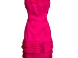 a pink dress on a mannequin stand with a white background