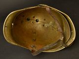 an old brass helmet on a black surface with a brown strap