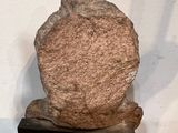 sculpture of a rock on a black stand on a brick floor
