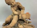 statue of a boy sitting on a rock holding a bird