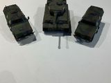 three toy army vehicles sitting on a white surface