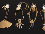 several gold necklaces and pendants on a black surface