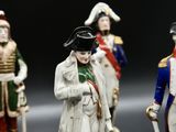 three figurines of men dressed in military uniforms stand in front of a black background