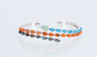 bracelet manchette en argent orné de pierres multicolores, sur un fond blanc