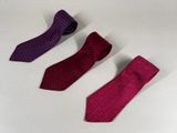 three ties are lined up in a row on a white surface