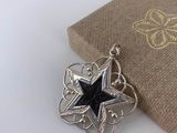 silver and black star pendant with a box on a white surface