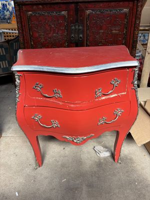 une vieille commode rouge au plateau argenté