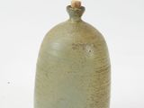 a small green vase with a wooden lid on a white surface