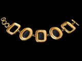 a gold necklace with black stones on a black background