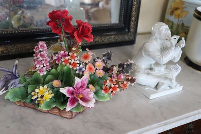 a vase with flowers on a table next to a statue of an angel