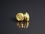un gros plan sur une paire de boucles d'oreilles en or posées sur une surface noire