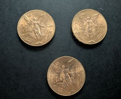 three gold coins sitting on top of a black surface