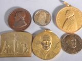 several different types of coins and medals are displayed on a white surface