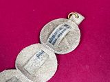 an image of a silver necklace with a tag on it on a pink surface