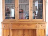 a large wooden cabinet with a book shelf on top of it