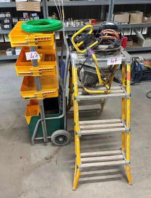 une échelle posée à côté d'un chariot sur lequel se trouvent des outils