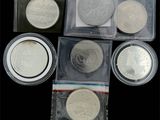 quatre types différents de pièces d'argent dans des sachets en plastique posés sur une surface noire