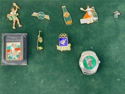 de nombreuses épingles et une montre posées sur une surface verte