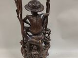an image of a statue of a man sitting on a tree stump