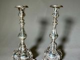 pair of silver candlesticks on a table with a gray background