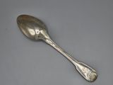 an antique silver spoon on a table with a gray background